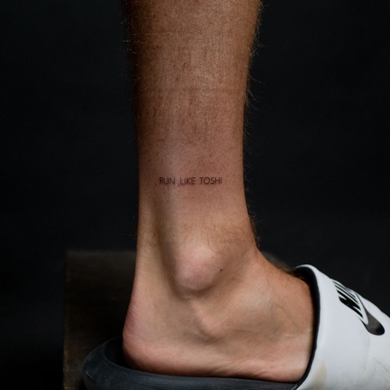 "Run Like Toshi" text ankle tattoo