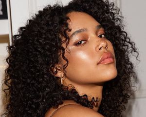 Woman with dewy, radiant makeup look and naturally curly hair