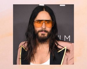 Jared Leto with a long, wavy hairstyle, peach blazer, and orange sunglasses