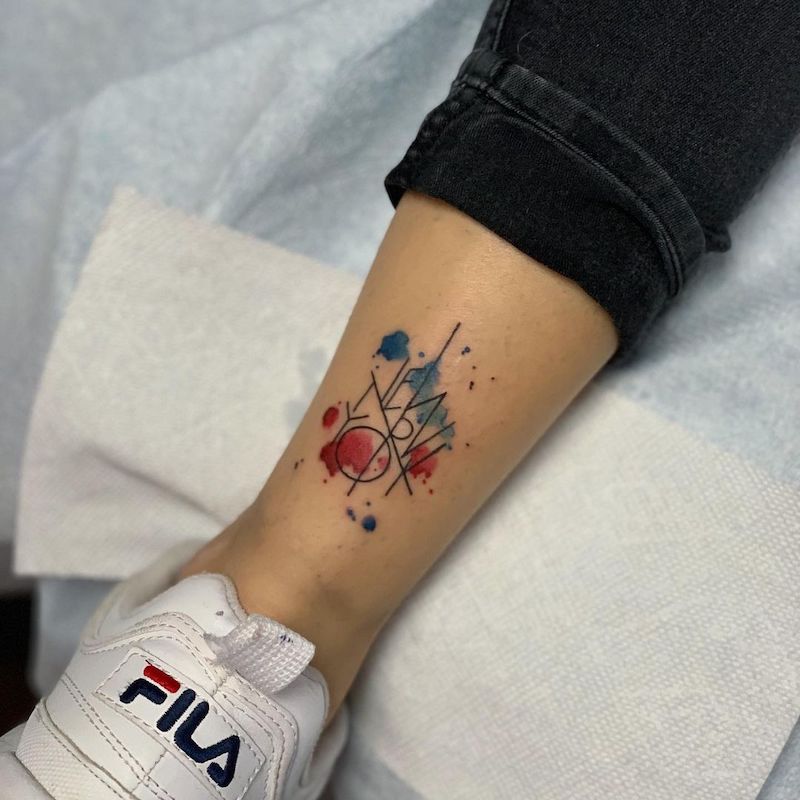 Red and blue watercolor ankle tattoo with "New York" text in all caps