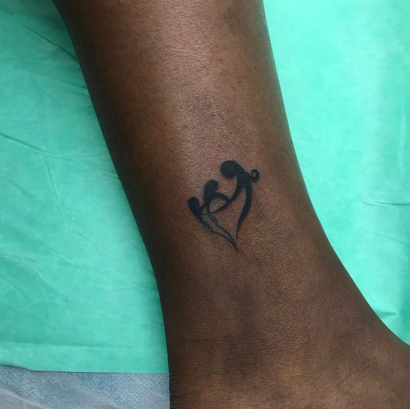 Ankle tattoo of blackwork figures holding hands