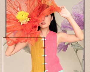 Model wearing a bright knit vest holdind oversized faux flowers.