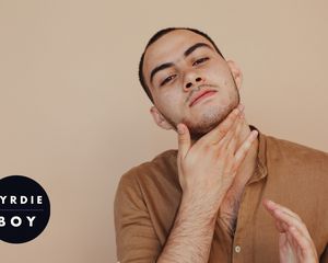 A masculine person applies oil to his beard.