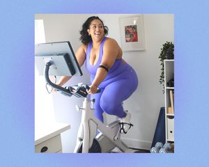 Woman in fitness clothing smiles on a stationary bike.