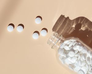 Biotin supplements scattered on a peach colored background.