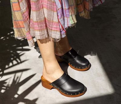 Model wearing black clogs and a plaid skirt.