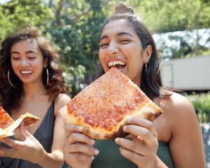 girls eating pizza in the park