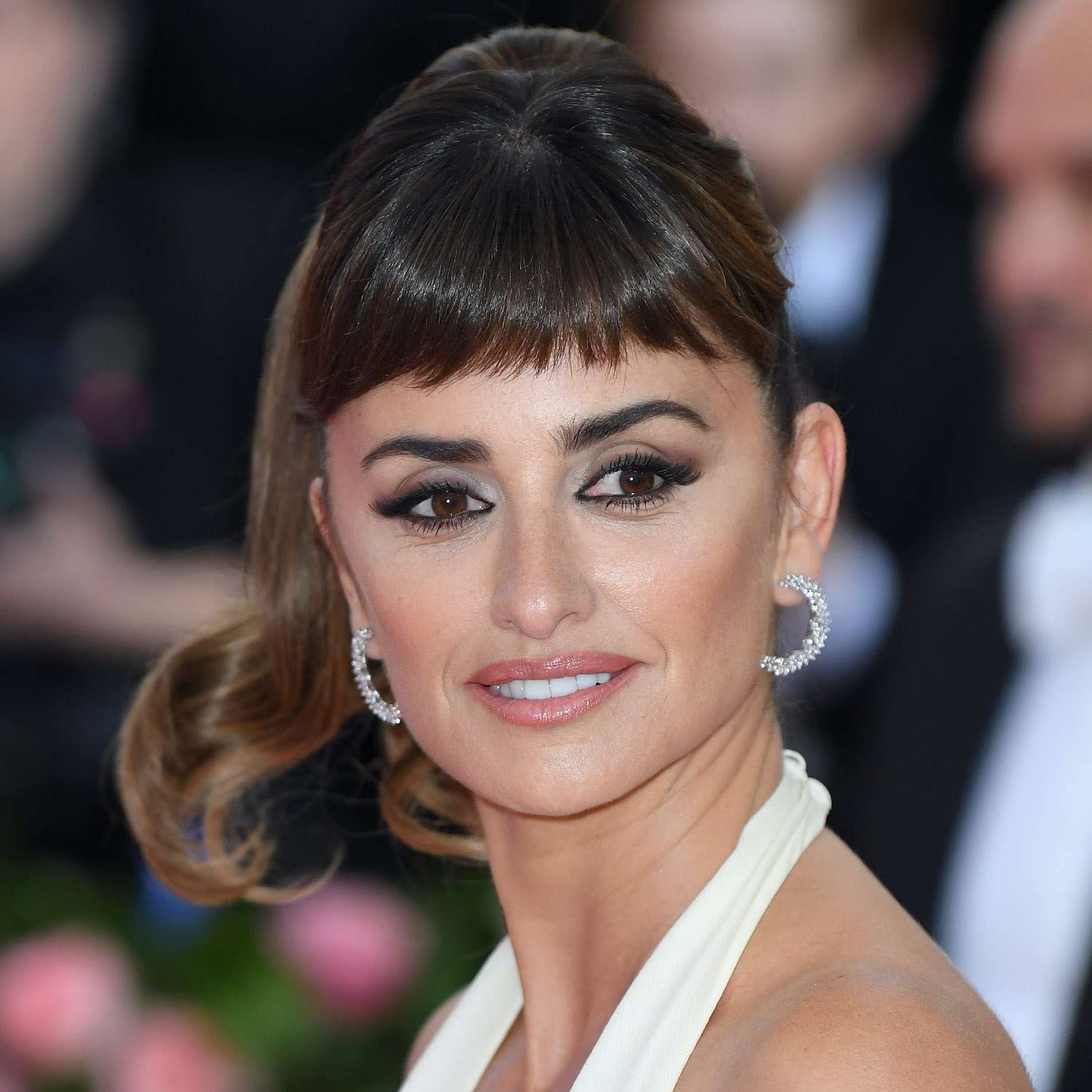 Penelope Cruz wears a blown-out ponytail with blunt baby bangs