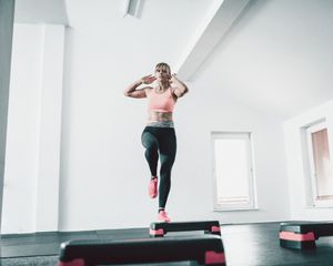 Woman in pink and black outfit doing step aerobics exercises