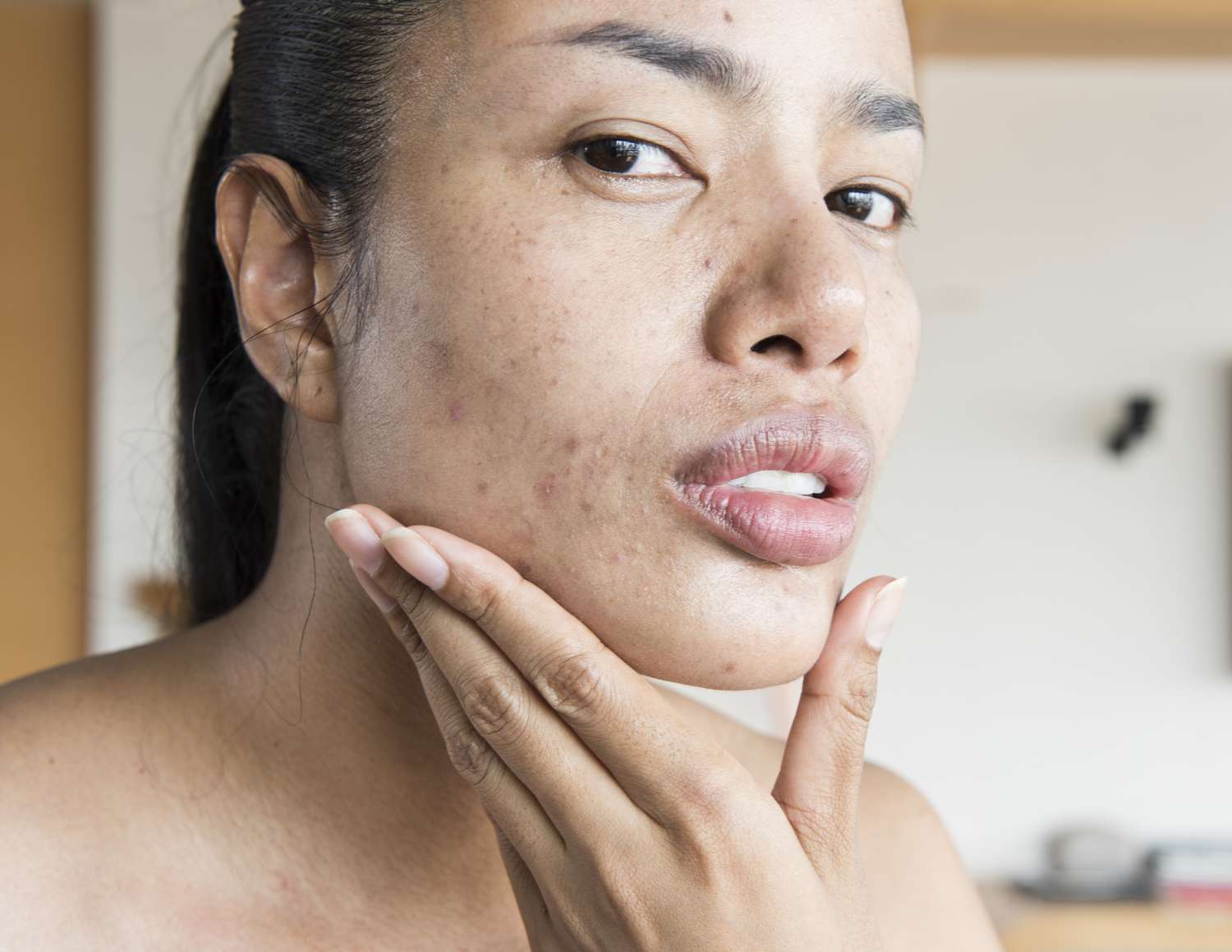 Woman looking at herself while holding her chin in her hand.