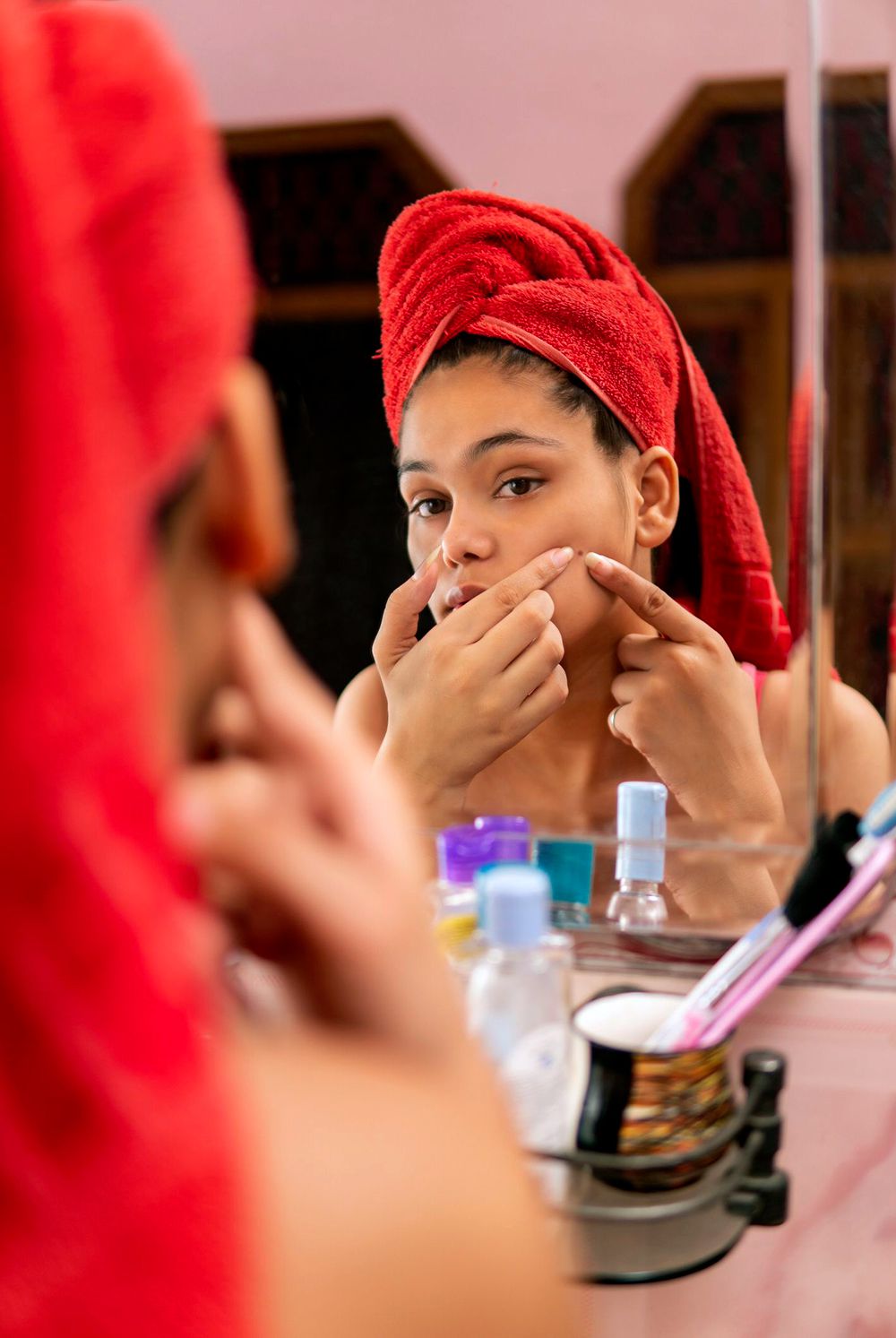 person popping a pimple in bathroom mirror