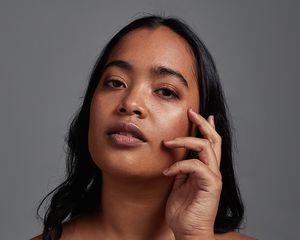 Woman with clear skin touches her face