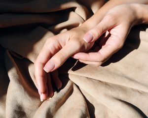 Hands with minimalist manicure on soft blanket
