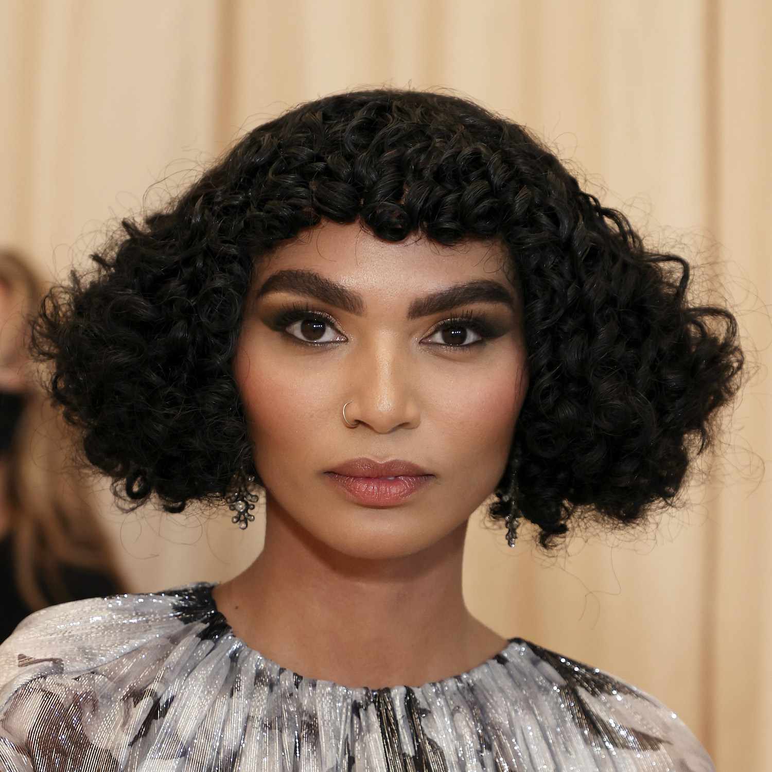 Sophia Roe wears a short curly bob hairstyle with baby bangs
