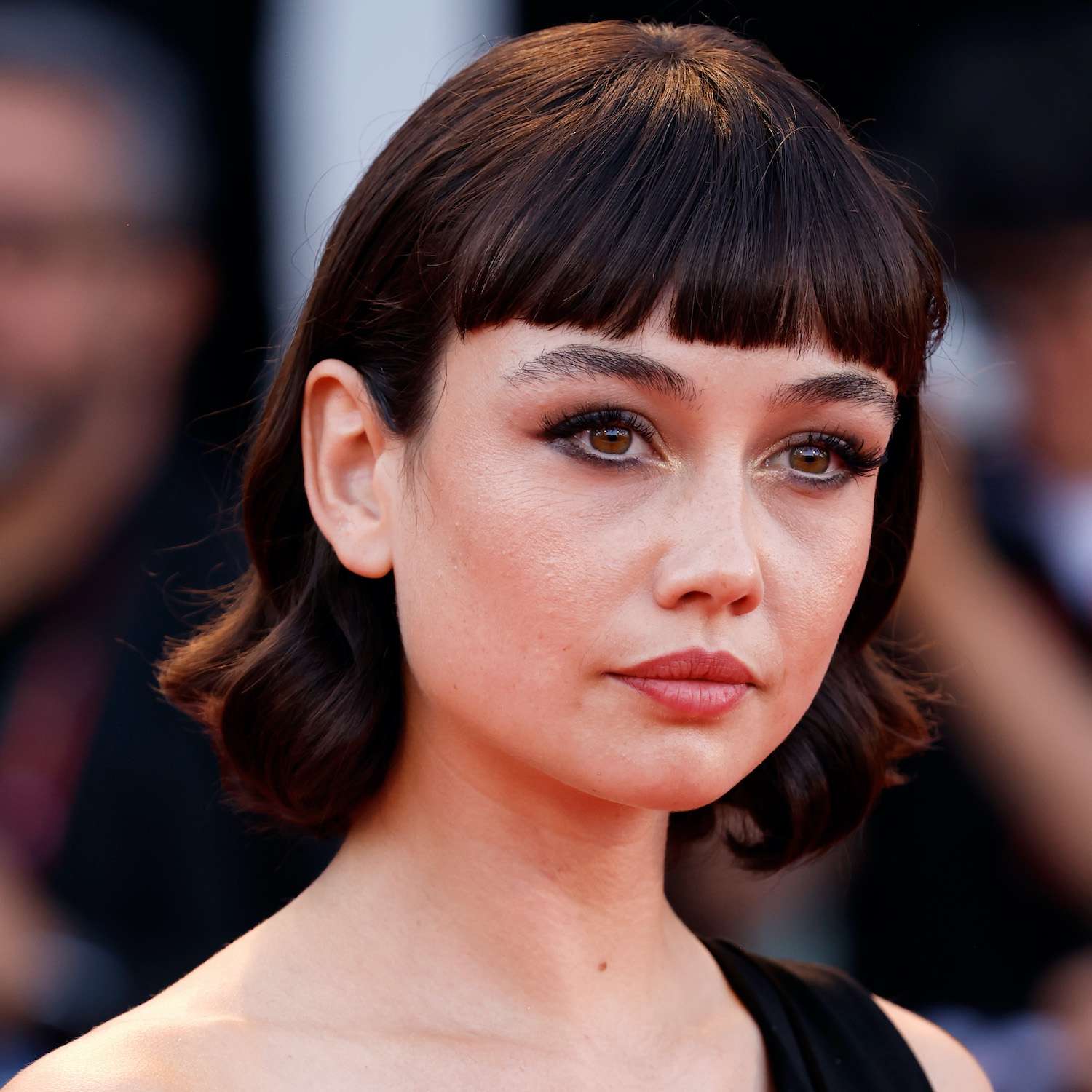 Sydney Chandler wears a curled bob hairstyle with baby bangs