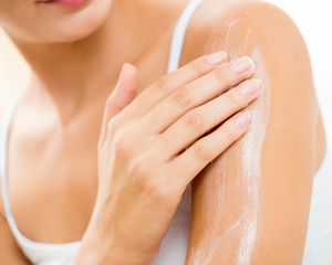 Person applying lotion to back of arm.