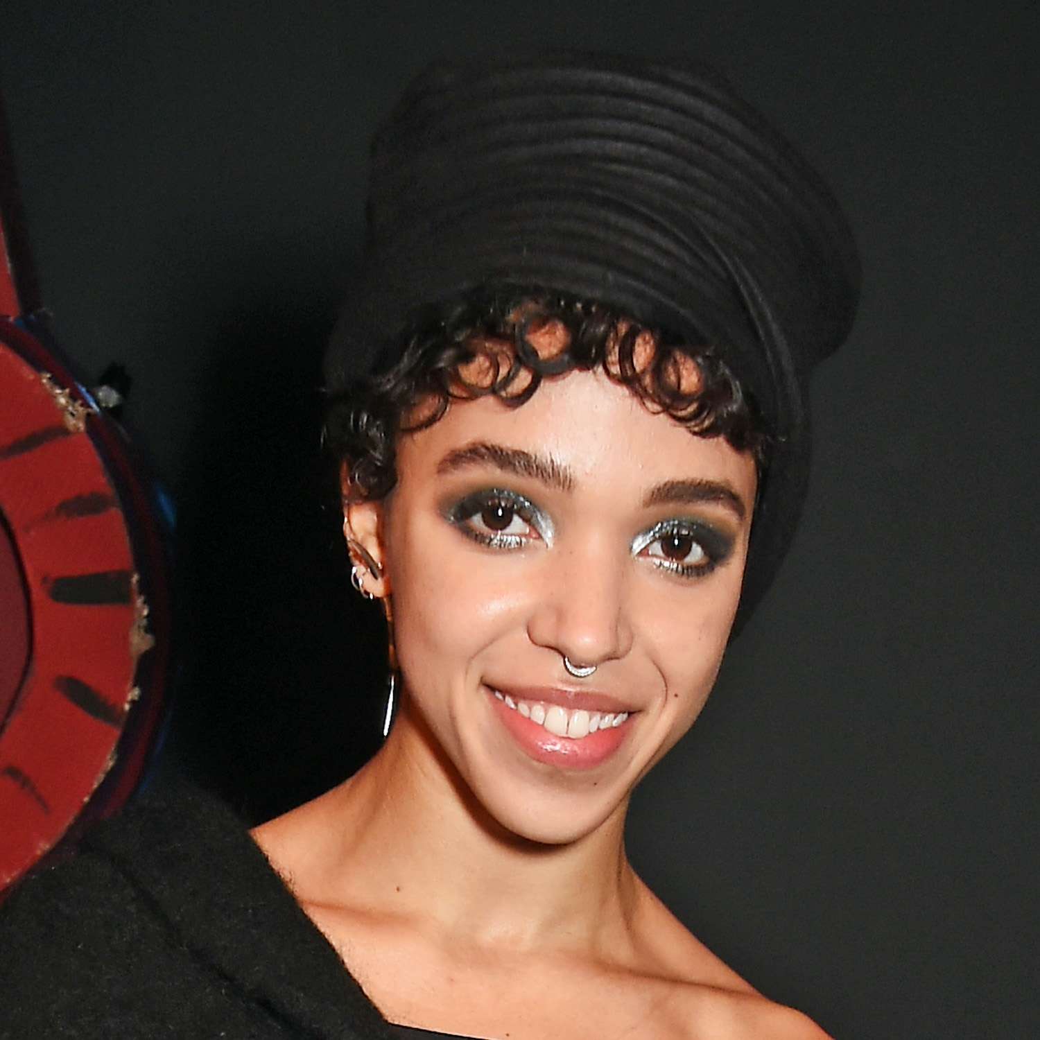 FKA Twigs wears a cropped haircut with pin-curled baby bangs and a hat