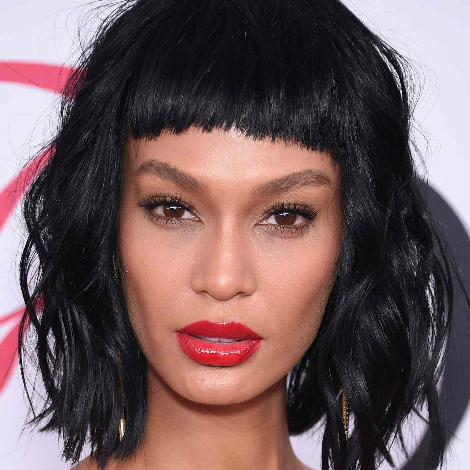 Joan Smalls wears a tousled bob with wavy lengths and straight baby bangs