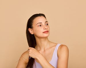 woman holding wet hair on a beige background