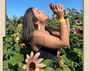 byrdie writer Aleenah Ansari smiles with flowers