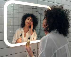 Woman applying oil to face