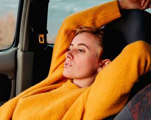 Woman in orange sweater reclining in car seat