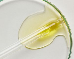 A yellow liquid in a petri dish with a dropper.