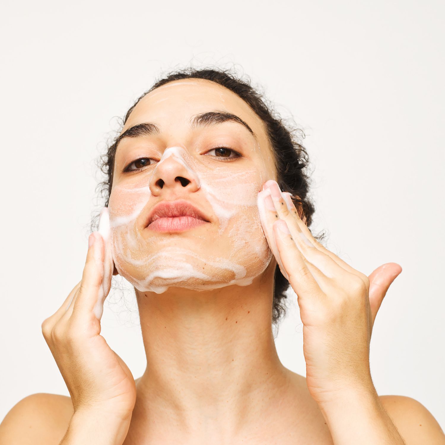 Photo of a person washing their face with a foaming cleanser