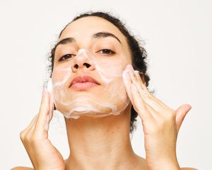 Photo of a person washing their face with a foaming cleanser