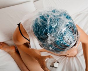 woman with hair dye on head on white bed sheets