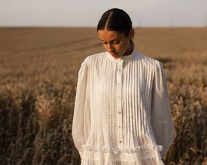 Woman wearing white linen dress standing in a field