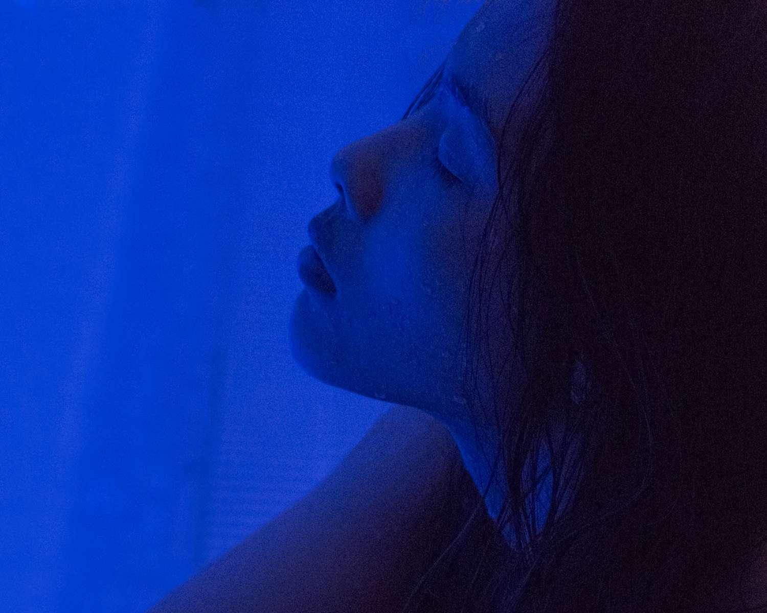 Side profile of woman's face in vibrant blue light