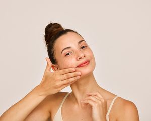 woman applying skincare product to cheeks