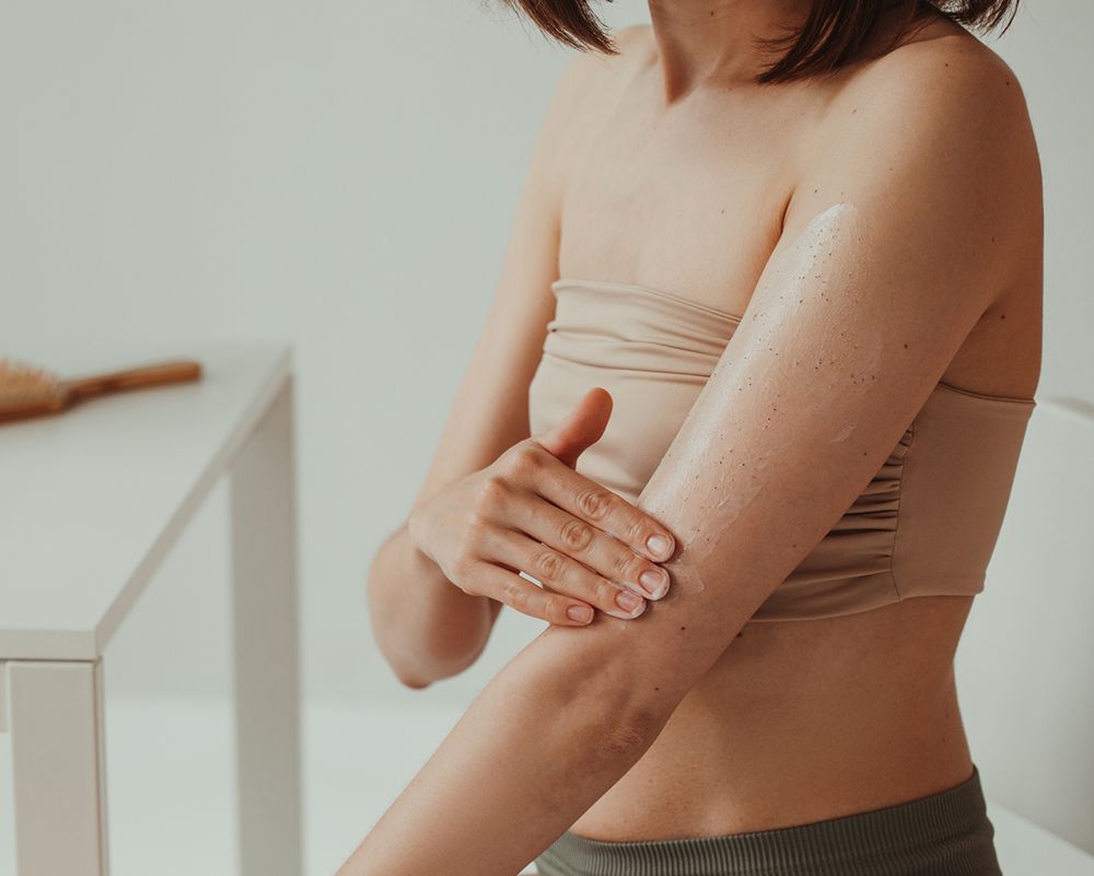 Woman applying lotion on her arm, moving toward her elbow.