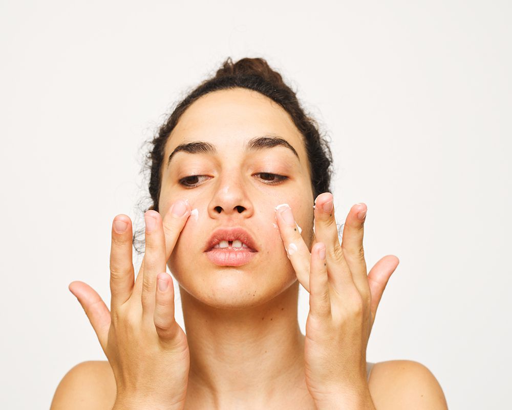 woman applying cream to cheeks