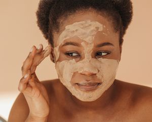 black femme applying clay mask