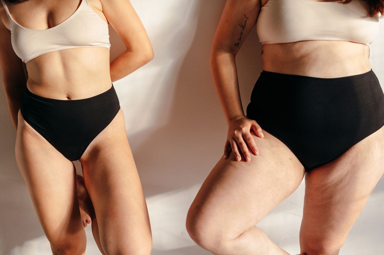 Two unidentifiable women in black briefs and beige bralettes.