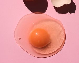 A cracked egg on a pink background