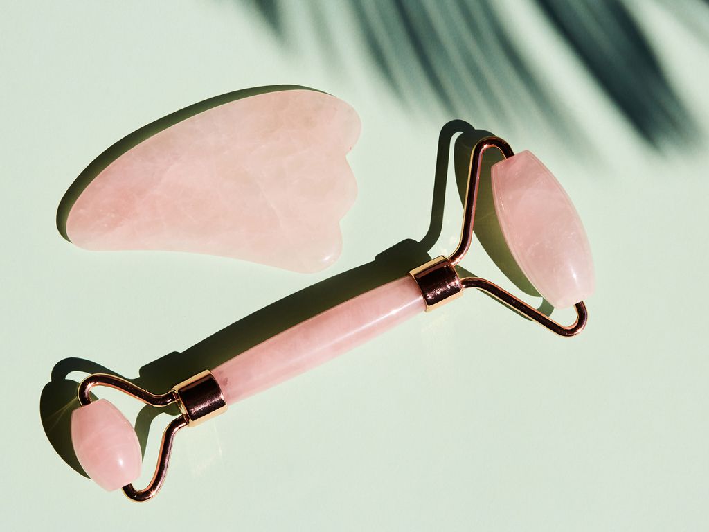 Rose quartz gua sha tools on a green background