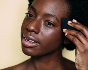Woman applying foundation with a blending sponge.
