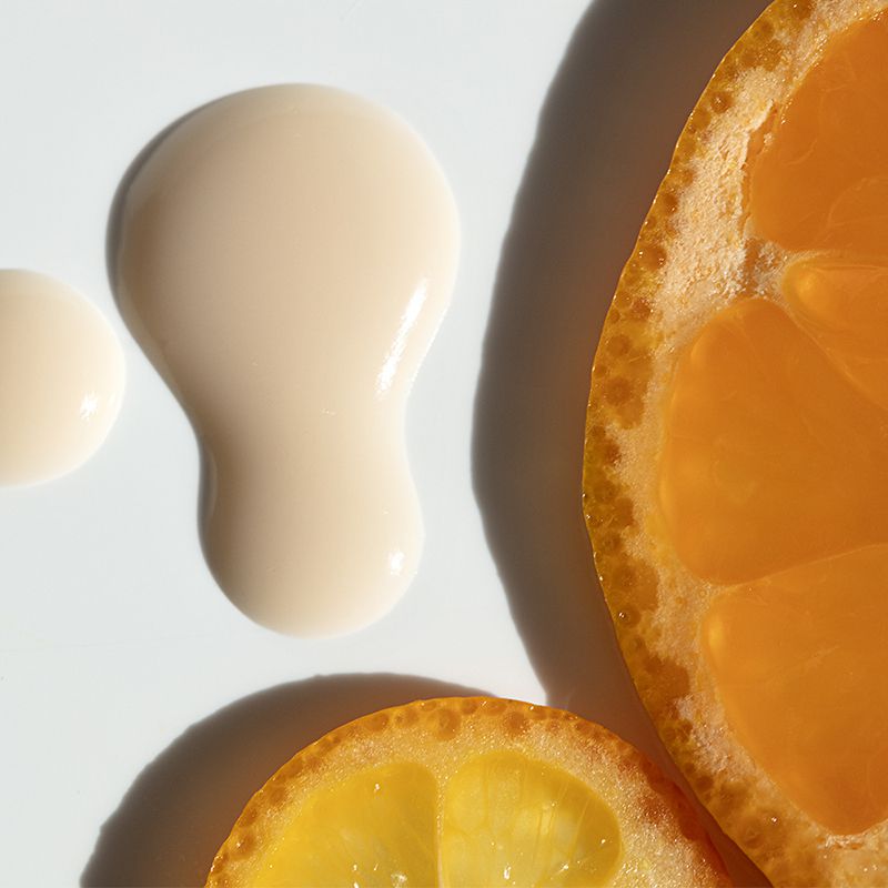 A drop of vitamin C serum beside orange slices