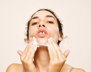 woman washing face with sudsy cleanser 