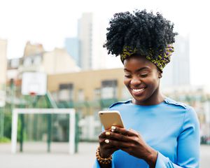 Woman looking down at her cell phone outside