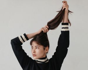Woman grabbing her hair above her head.
