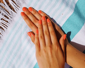 hand with coral manicure on a striped towel
