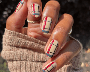 woman with red and tan sweater nail design